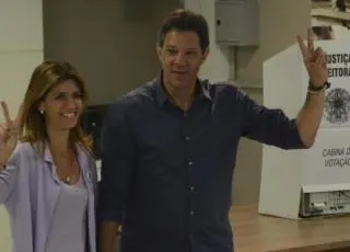 Com camisa azul, Haddad vota e faz sinal de vitória